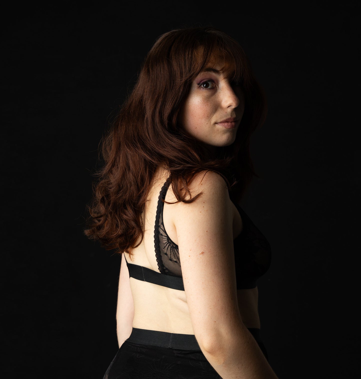 Woman wearing a black bra and shorts against a black background