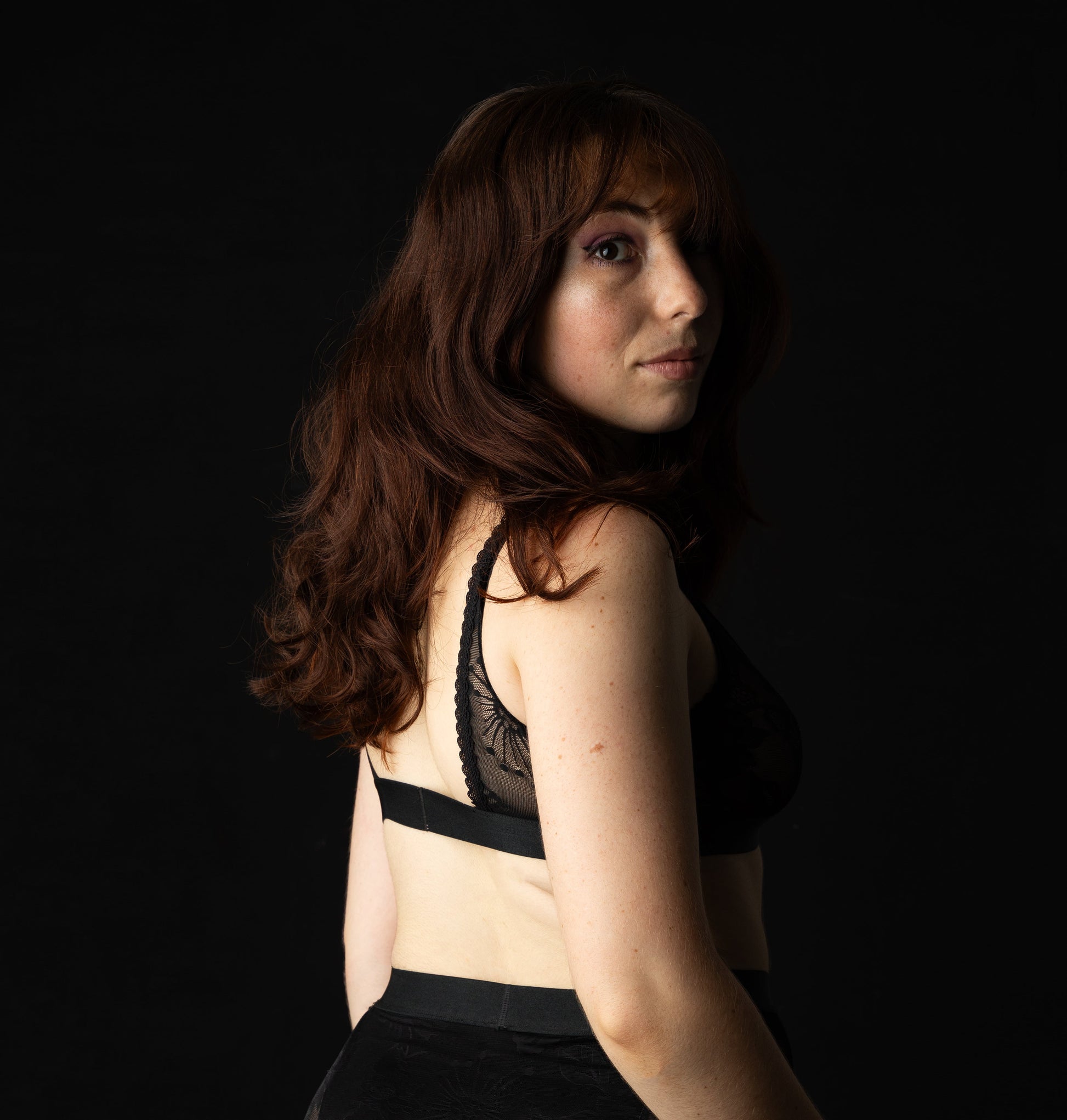 Woman wearing a black bra and shorts against a black background